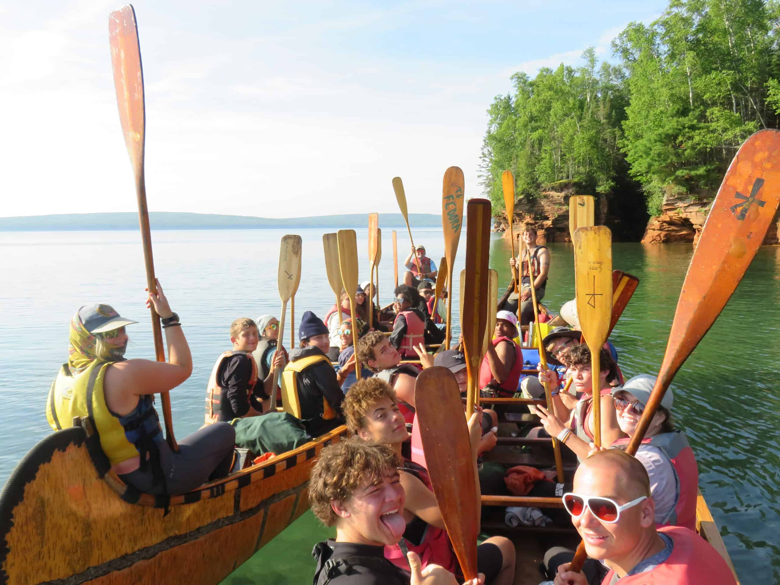 Group of people enjoying a scenic boat ride on Lake Minnetonka near Incarnation Lutheran Church, surrounded by lush green trees and clear blue water.
