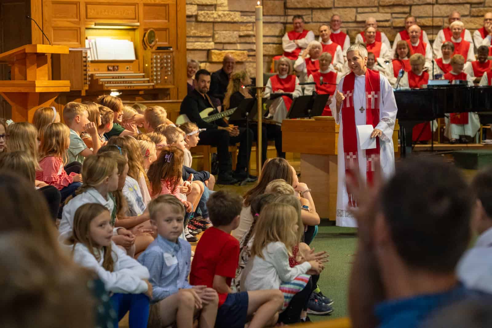 Children attending a church service at Incarnation Lutheran Church with a pastor and choir in the background.