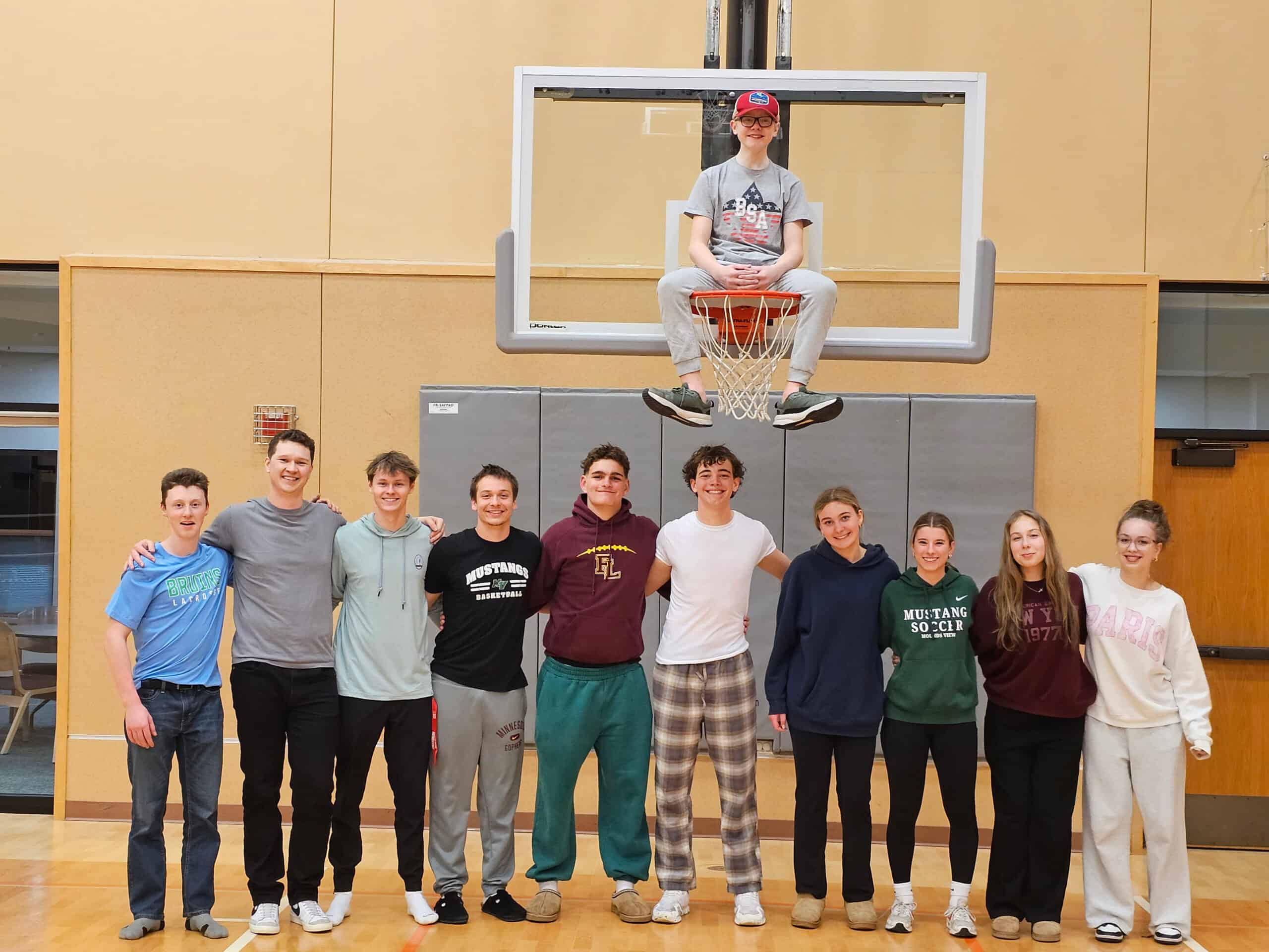 Group of young basketball players standing in front of a basketball hoop in the gym at Incarnation Lutheran Church, showcasing youth sports and community engagement.