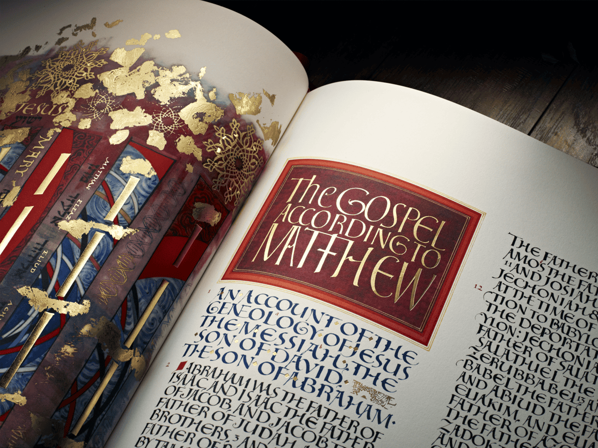 Open Bible with gold and red decorative cover displaying "The Gospel According to Matthew" on a wooden table.