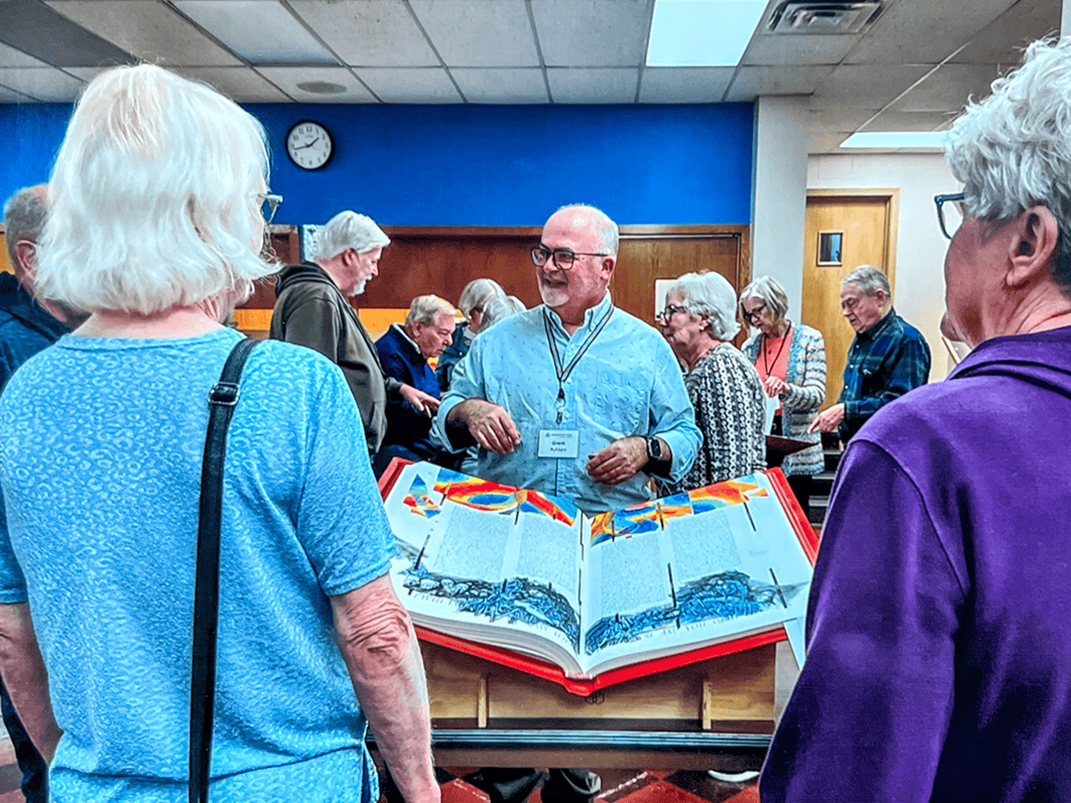 Community gathering at Incarnation Lutheran Church with seniors engaging in a social event and sharing stories around a large open book display.