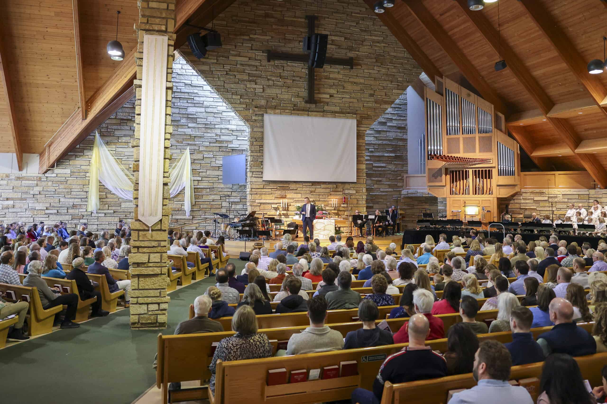 Incarnation Lutheran Church interior during service with congregation and choir, showcasing wooden architecture and large organ pipes.
