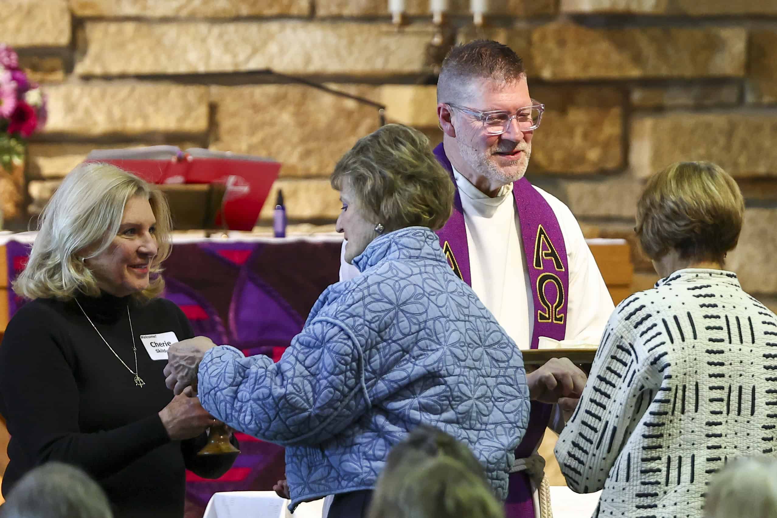 Celebrant pastor at Incarnation Lutheran Church delivering a sermon with colorful abstract banners in the background.