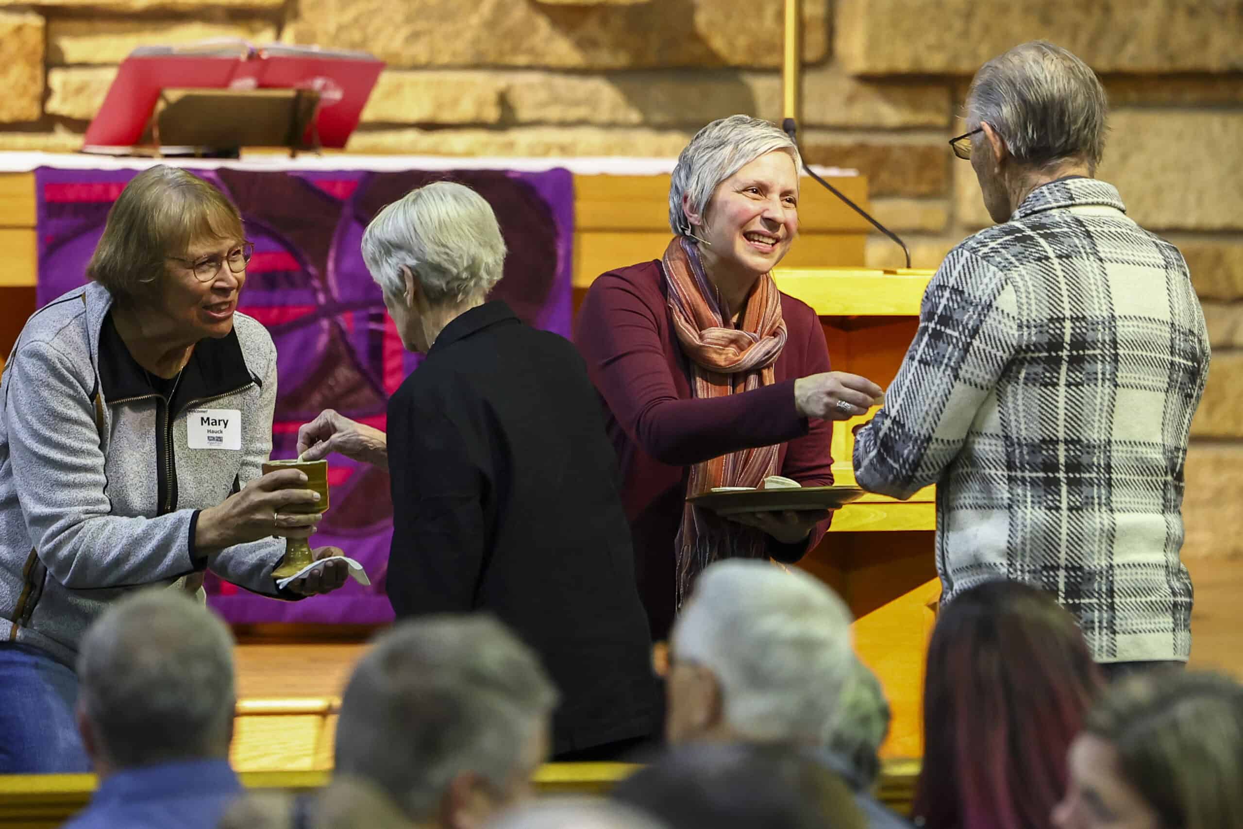 Elderly congregation attending a service at Incarnation Lutheran Church, with a pastor speaking at the altar in a warm, welcoming church setting.