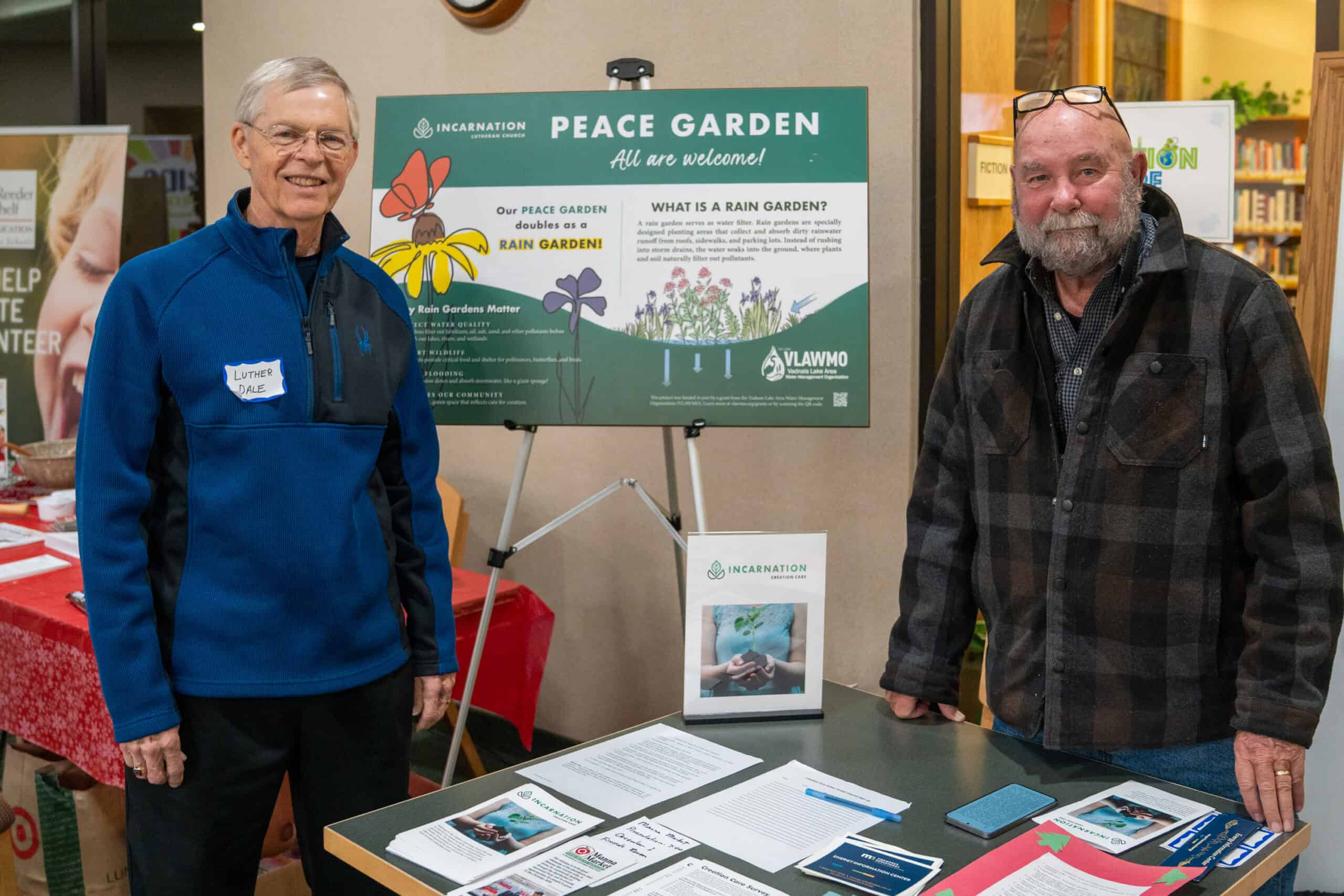 Incarnation Lutheran Church Peace Garden event with two smiling men standing beside informational display.