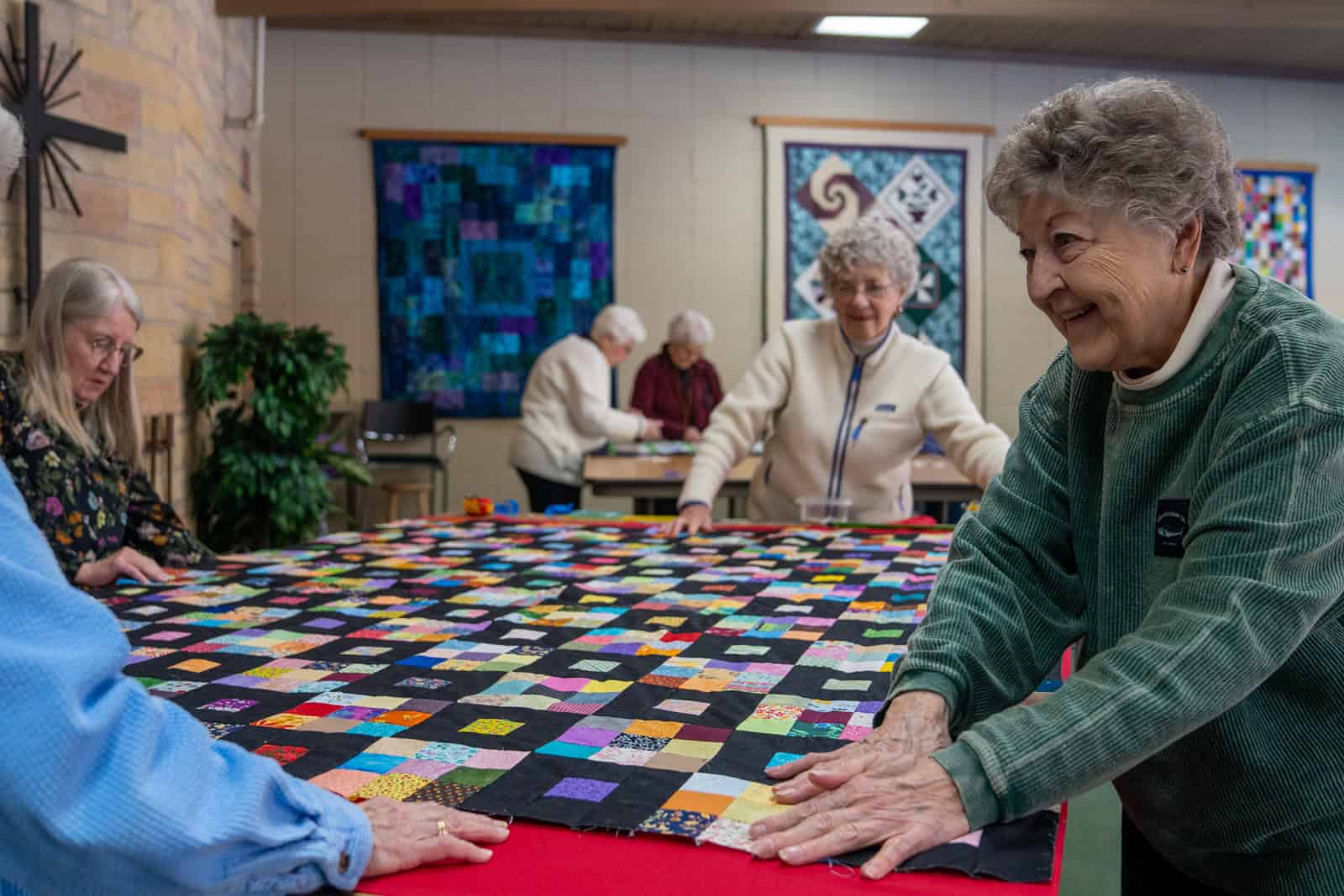 Senior women working together on a colorful quilt at Incarnation Lutheran Church community event.