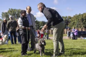 People at Incarnation Lutheran Church outdoor event with dogs, engaging in a training or social activity on a sunny day.